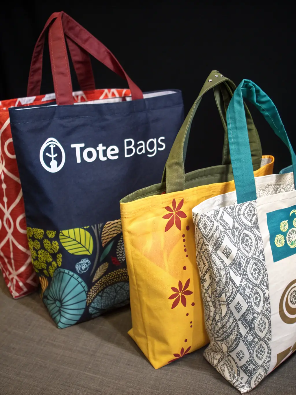 A vibrant image of custom-printed tote bags with various company logos, ideal for trade shows and events.